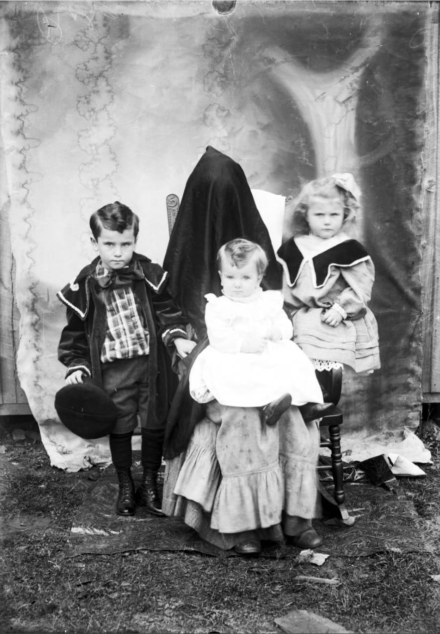 Djeca na portretu Alberta J. Ewinga s odraslom osobom skrivenom ispod pokrivala, oko 1896.–1912.